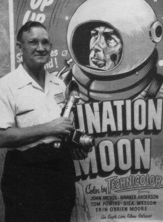 In front of a Destination Moon poster stands author E.E. Smith, SF author whose works were an inspiration for the video game Spacewar!